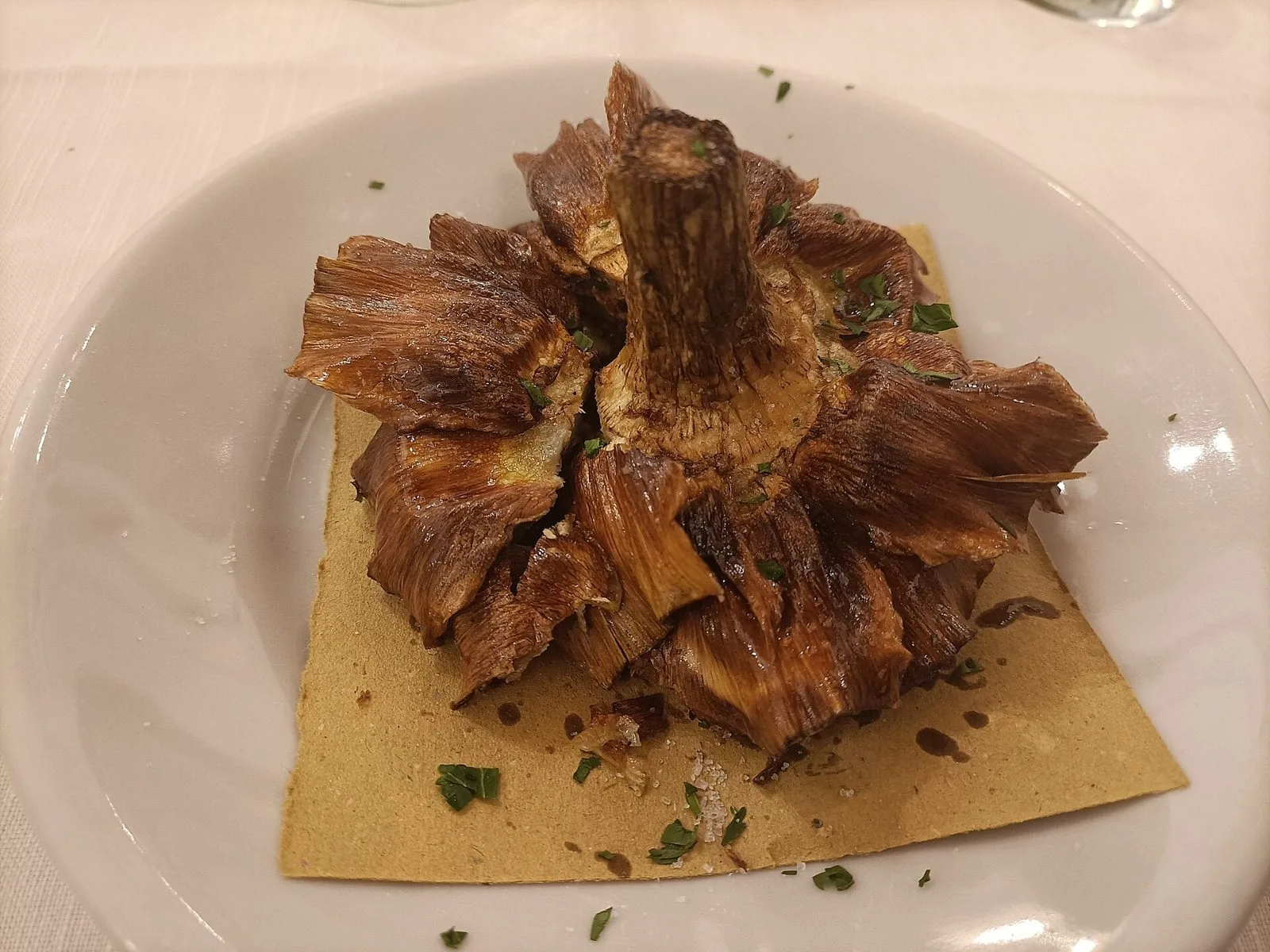 Carciofo alla giudia fritto servito su un piatto bianco