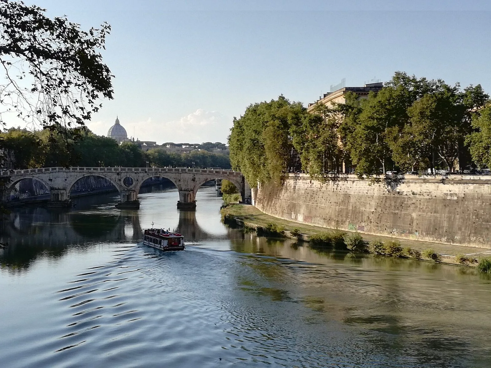 Il Tevere a Ponte Sisto in una giornata estiva, con un battello e la cupola di San Pietro sullo sfondo